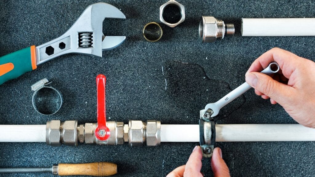 Plumber repairing a pipe valve with an adjustable wrench in Douglasville