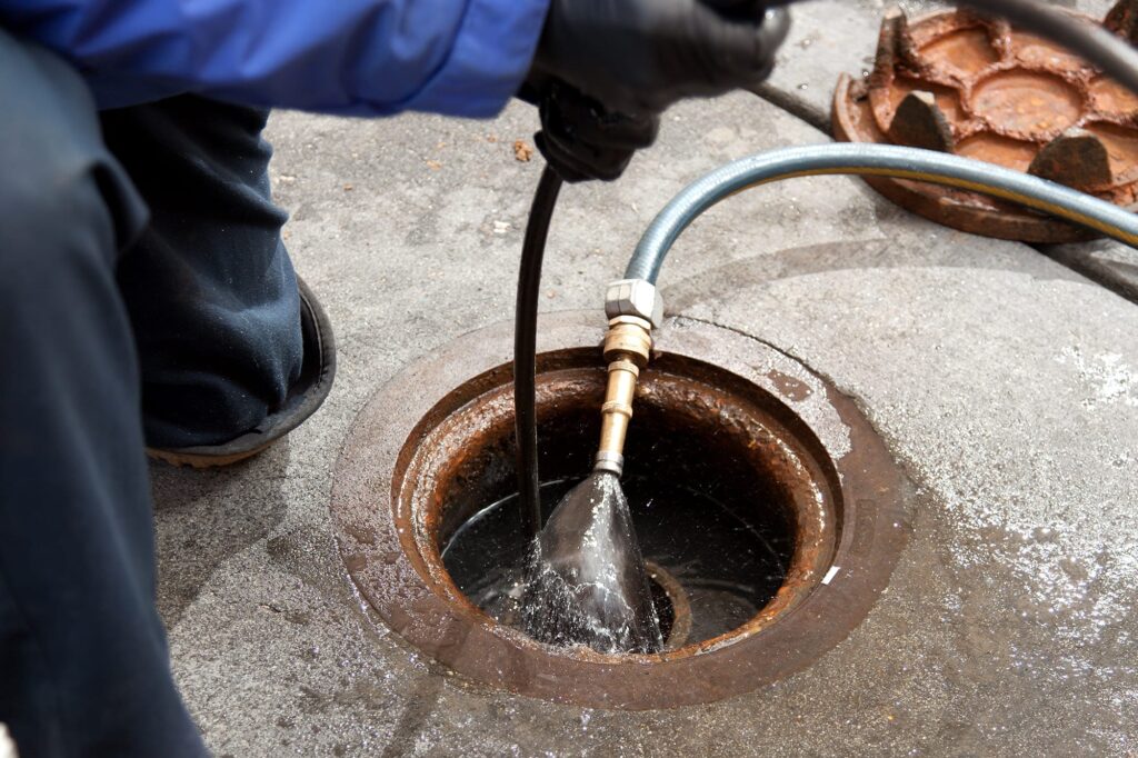 Plumber hydro jetting a sewer line through a manhole in Douglasville
