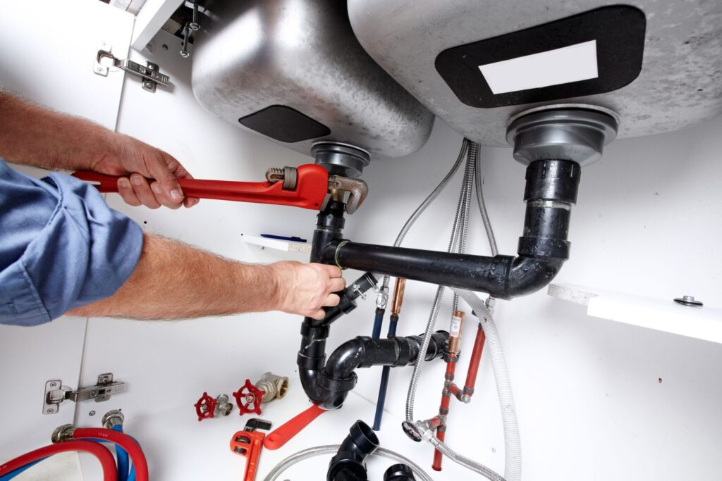 Plumber repairing drain pipes beneath a kitchen sink in Douglasville