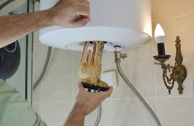 Technician removing mineral buildup from a water heater in Douglasville