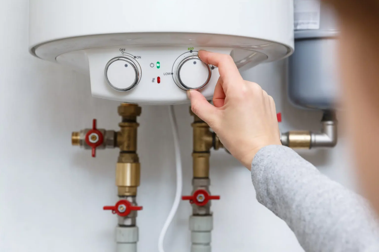 Homeowner adjusting the temperature controls on a water heater in Douglasville